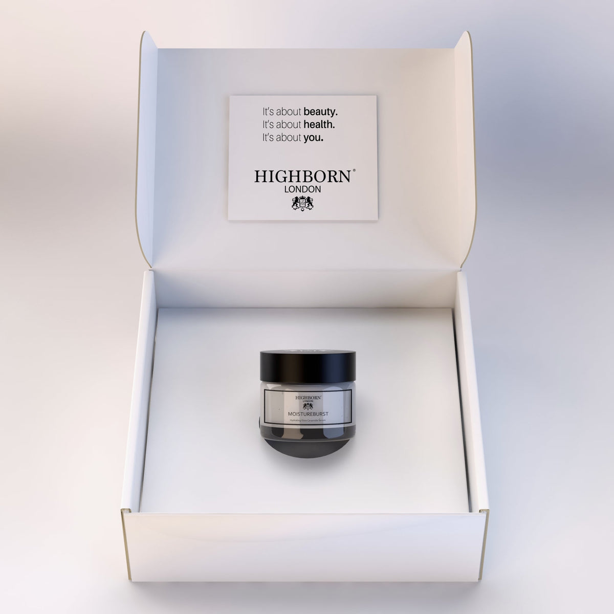 Highborn London MoistureBurst Hydrating Glow Ceramide Serum jar centred inside an open white presentation box with lid text reading "It's about beauty. It's about health. It's about you."